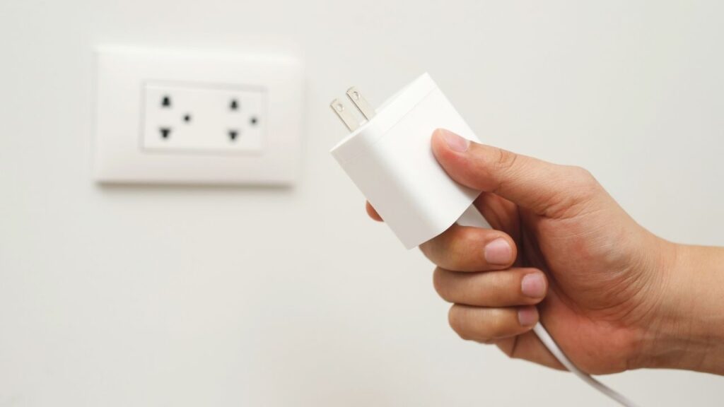 Image of unplugging a charger by Canva. 
Tips for sustainable living at office - unplug charger and power adapters  #sustainableliving #ecofriendlylivingtips #sustainablewaystolive #sustainabletips #wecareearth 